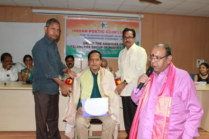 Felicitation on stage with a shawl and flowers